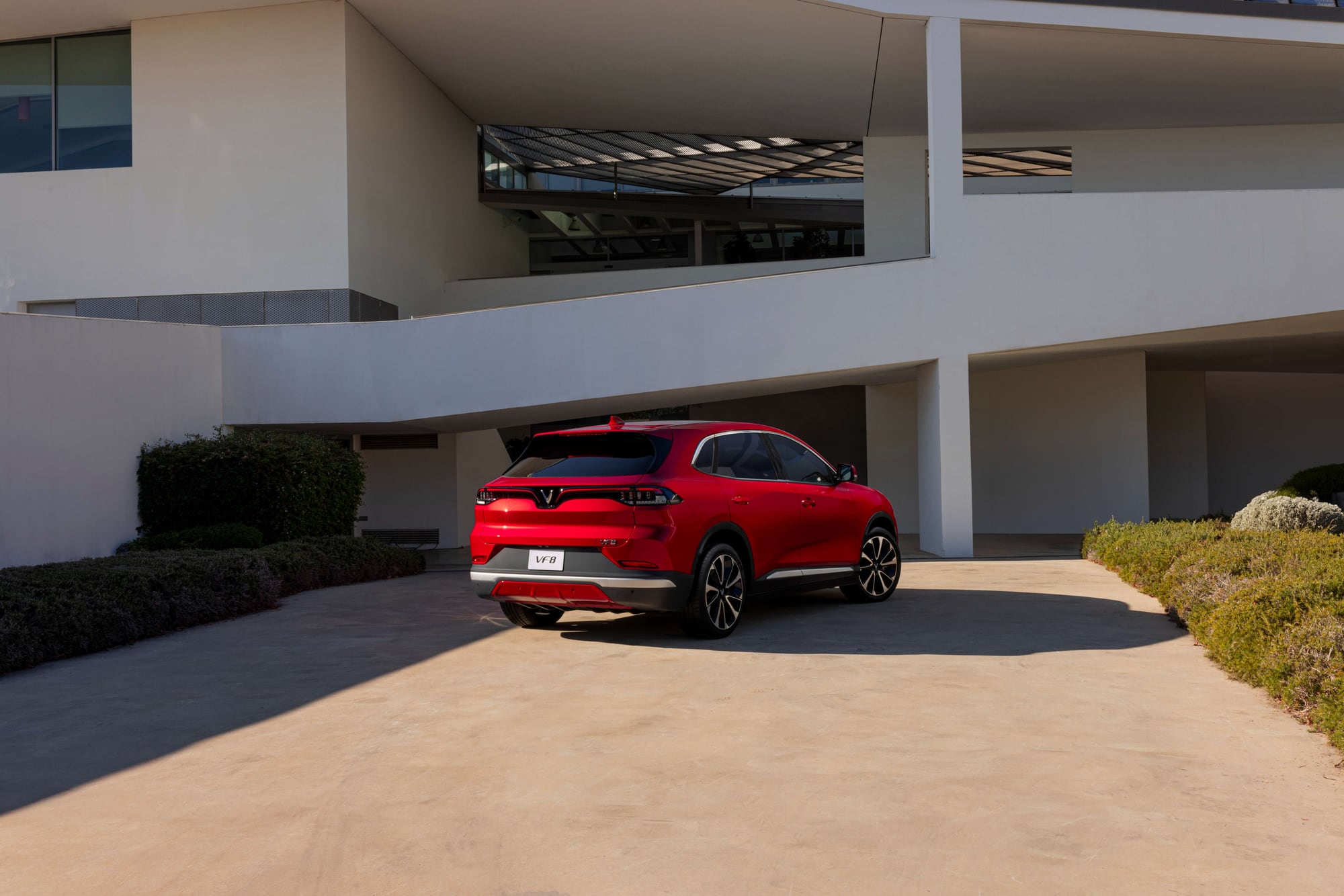 VinFast VF 8 in red, rear three-quarter view showing the LED taillight bar